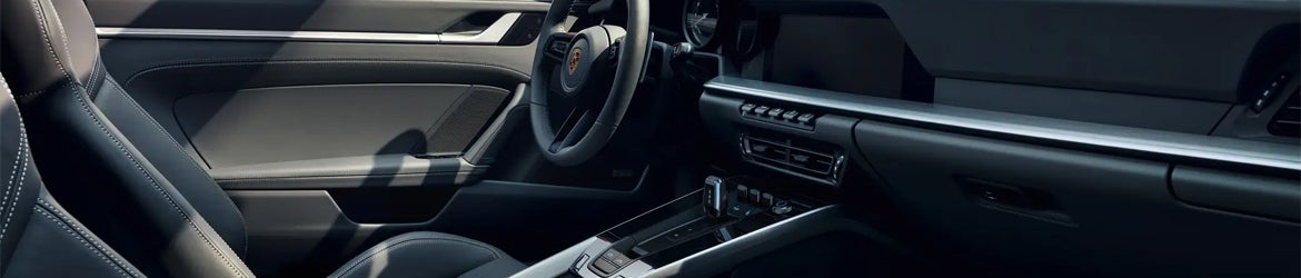 The sleek black interior of a luxury car, showing the driver's seat, steering wheel, and dashboard.