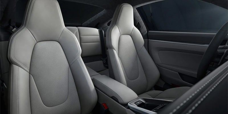 Interior of a car with light gray leather seats, black dashboard, armrest, and steering wheel.