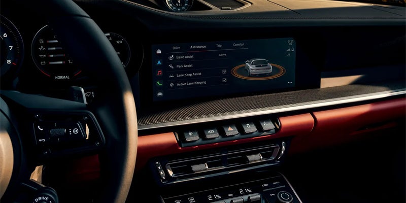Dashboard of a modern car with a digital display showing driver assistance features and a blurred steering wheel.