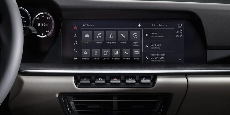 Dashboard of a car showing a digital instrument cluster, a large central touchscreen with app icons and a small info panel, and physical control buttons below it.