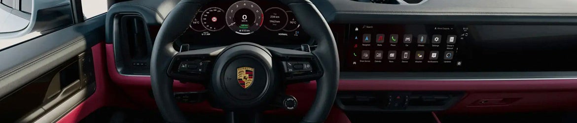 Interior of a Porsche car featuring a steering wheel with a logo, digital dashboard, and a touchscreen display.