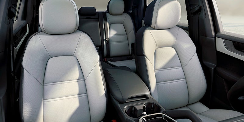 Vehicle interior showing light gray and dark gray two-tone bucket seats, front and back, with a center console.