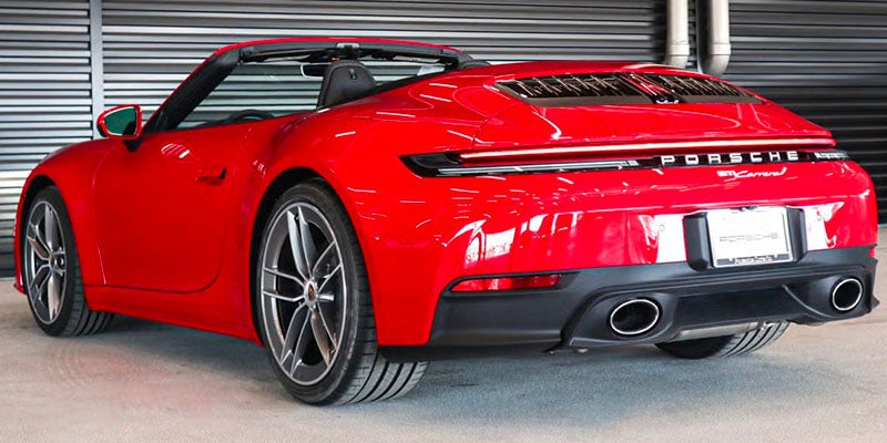 Rear view of a shiny red Porsche 911 Carrera convertible with its top down, parked indoors.