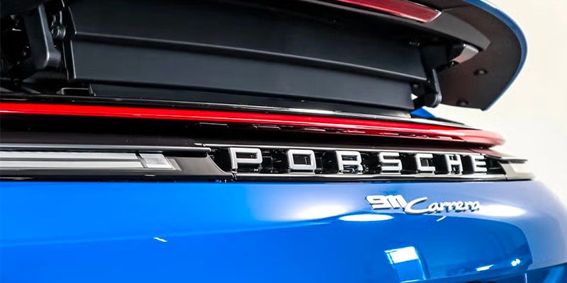 The rear of a bright blue Porsche 911 Carrera, showing the "PORSCHE" and "911 Carrera" emblems.