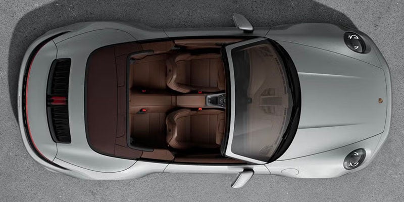 Overhead shot of a silver convertible sports car with its top down, revealing brown leather seats.