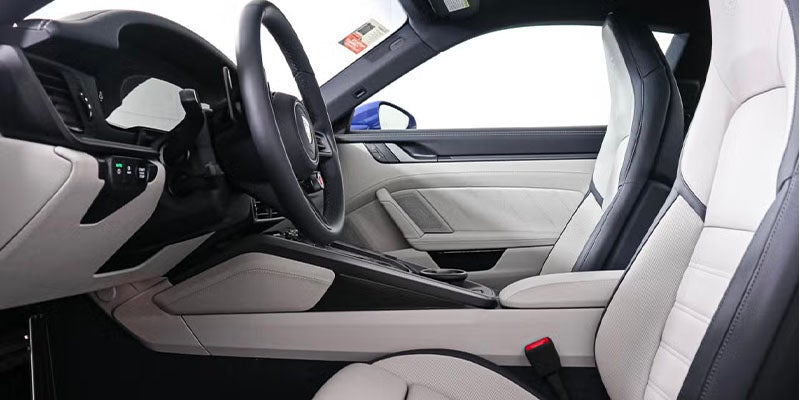 Interior of a modern car, showing the dashboard, steering wheel, and two-tone black and white seats.