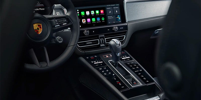 The interior of a high-end car with a large infotainment screen displaying app icons, steering wheel, and shifter.