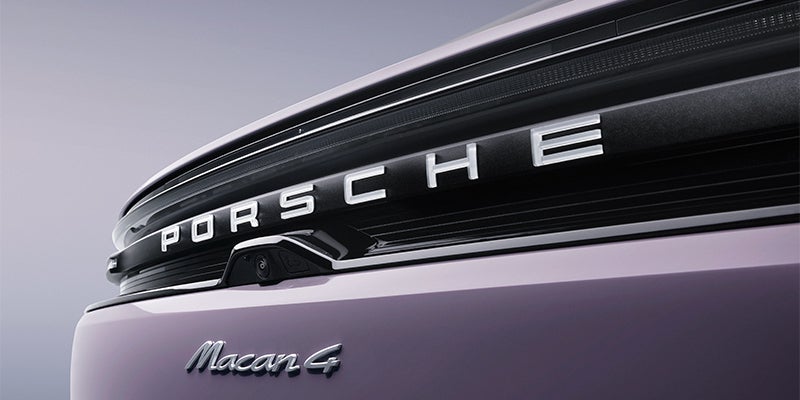 Close-up of the rear of a lavender-colored Porsche Macan 4, showing the "PORSCHE" and "Macan 4" emblems.