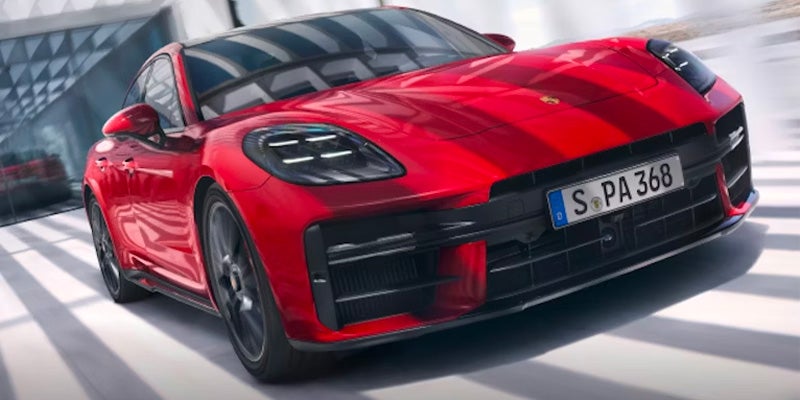 Front view of a sleek red sportscar with a black roof and German license plate, in motion.