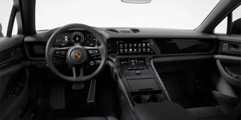 Dark interior of a Porsche Panamera, showing a steering wheel, digital dashboard, and infotainment screen.