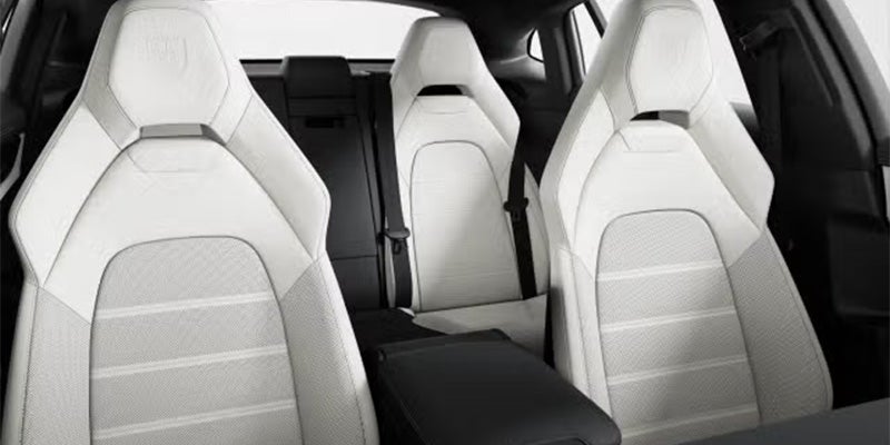 Interior of a vehicle, showing four white and gray striped bucket seats with seatbelts, and a black armrest.