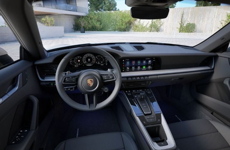 Interior view of a modern sports car cockpit with a dark gray dashboard, steering wheel, and infotainment screen.