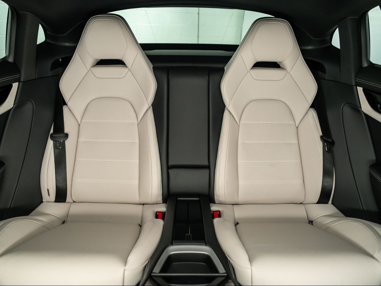 View from the back of a luxury car, showing two off-white leather bucket seats with black accents.