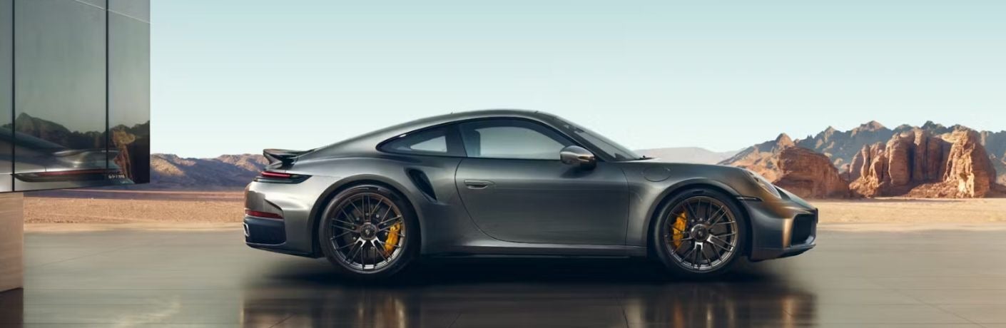 Side view of a dark gray Porsche 911 in a desert landscape.