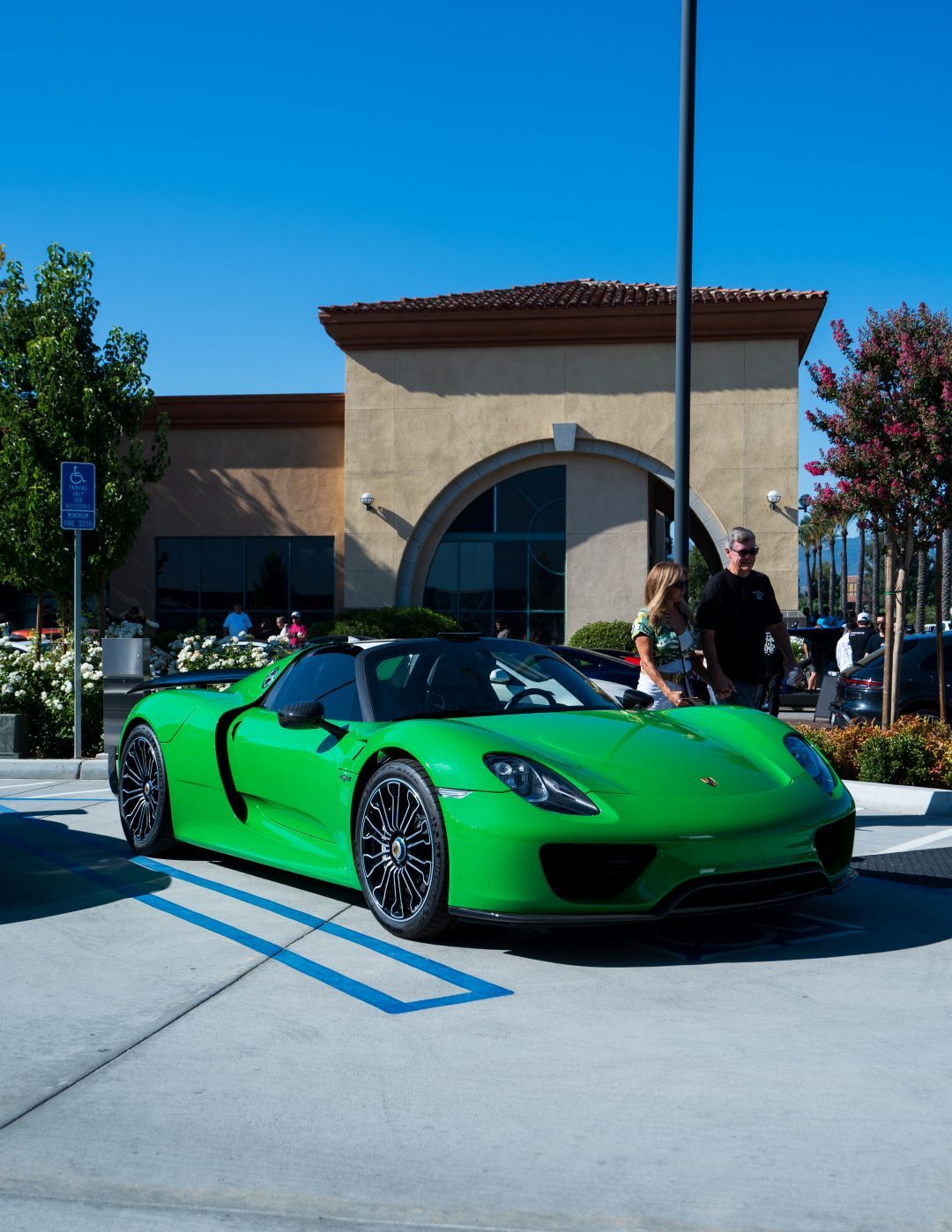 A bright green Porsche 918 Spyder sports car parked in an outdoor lot on a sunny day.