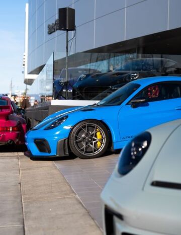 A bright blue sports car sits parked on a paved road next to other vehicles.