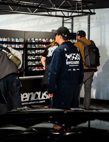 Three people in workwear examine a display of colorful sneaker boxes.