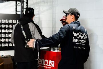 Two people wearing hats and sunglasses discuss while standing in front of a store display.