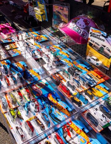 Rows of new and vintage Hot Wheels cars are displayed for sale at a flea market.