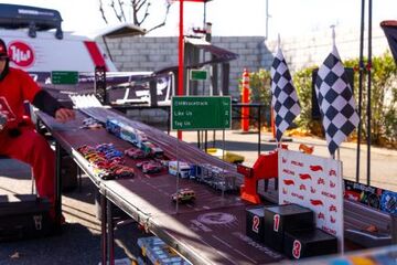 A person sets up a race track with toy cars and checkered flags for a competition.