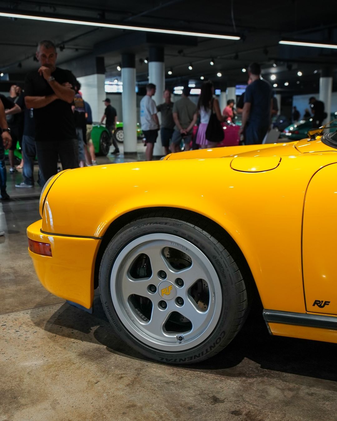 The front quarter of a bright yellow RUF Porsche, featuring a silver multi-spoke wheel with RUF branding.