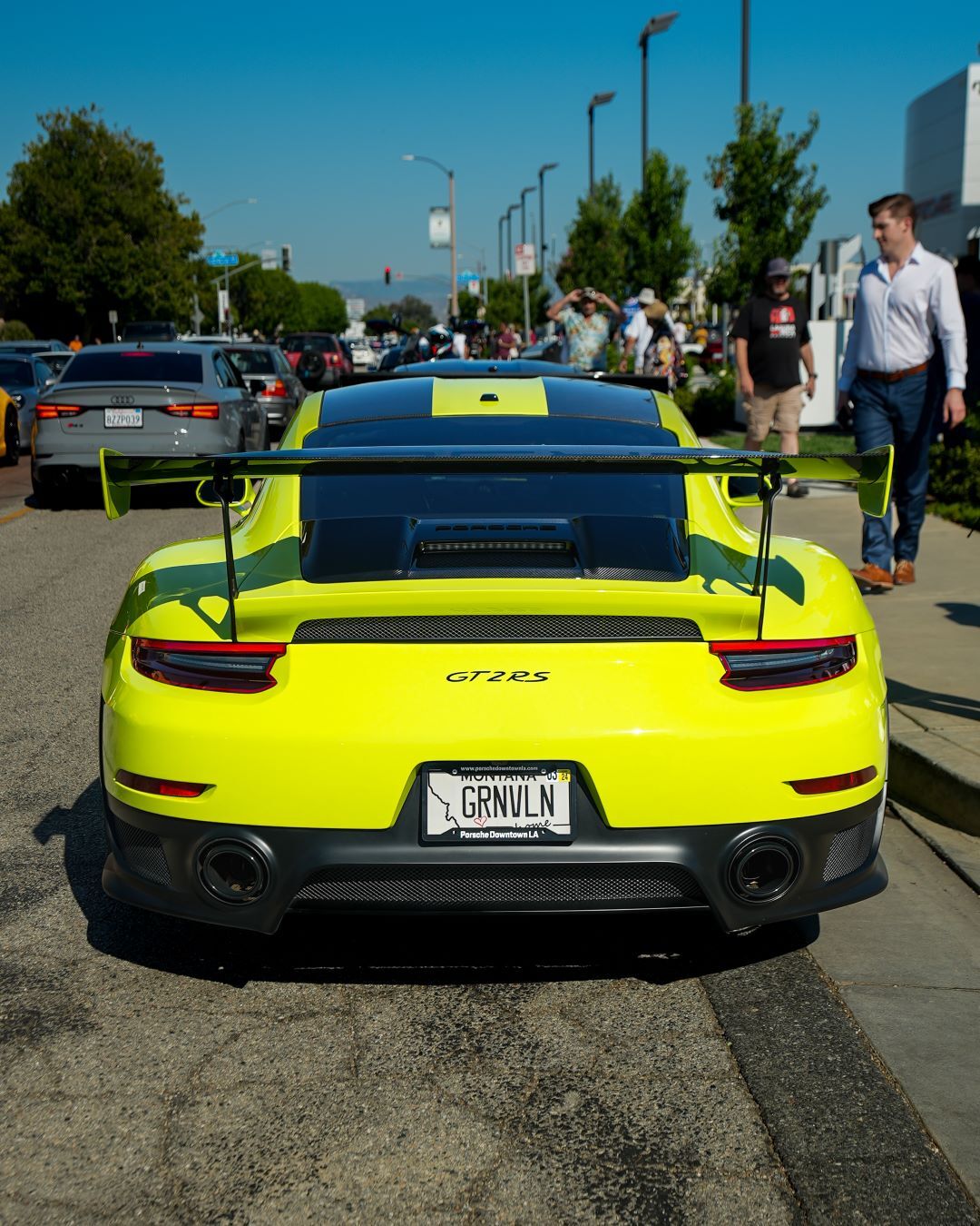 Bright yellow Porsche 911 GT2 RS sports car from behind, with a rear spoiler and black stripe, on a street.