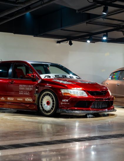 A red, tuned Mitsubishi Lancer Evolution sits in a brightly lit showroom.