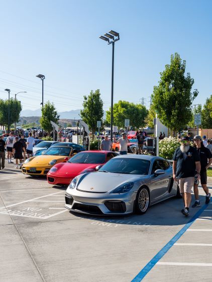 Several luxury sports cars are parked in a lot during a car show with people admiring them.