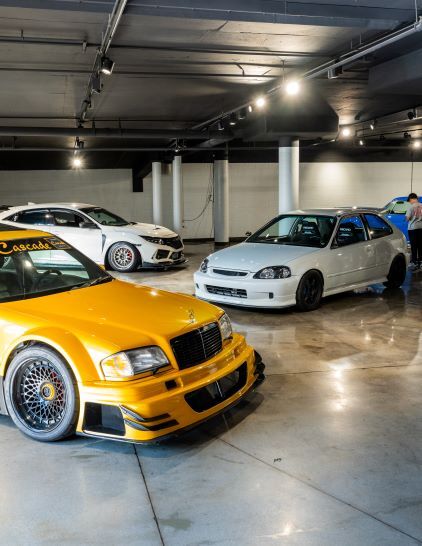 Several customized cars are displayed in a spacious, well-lit garage.