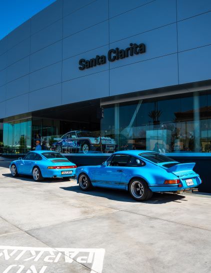 Two blue Porsche cars are displayed in front of a building labeled 'Santa Clarita.'