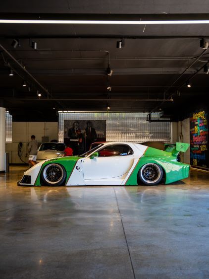 A customized white and green sports car sits in a sleek, modern garage.