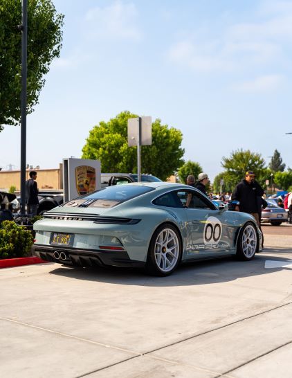 Light green Porsche sports car with '00' on the doors, parked outdoors at a car show.