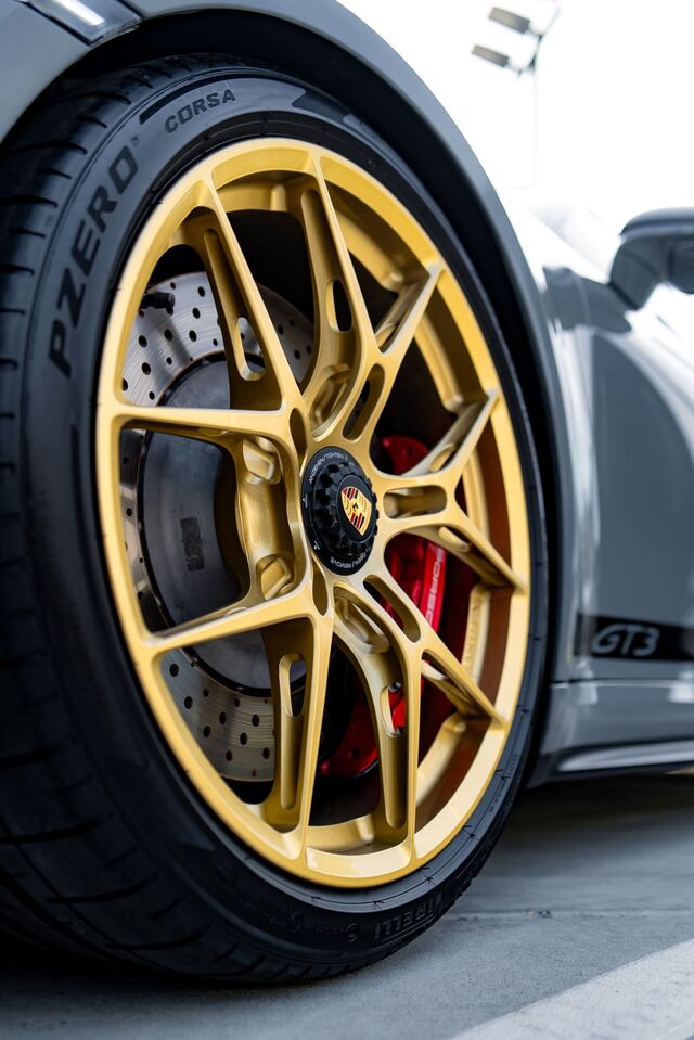 A detailed view showcases a Porsche GT3's yellow alloy wheel with black tires and large brake rotors.