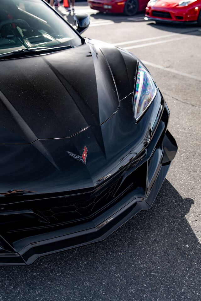 A black Chevrolet Corvette's hood and front lights are angled toward the camera.