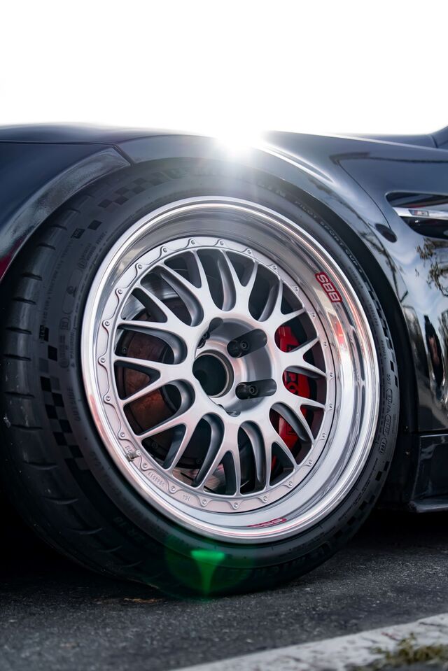 A close-up shows a shiny silver wheel and tire on a dark gray vehicle.