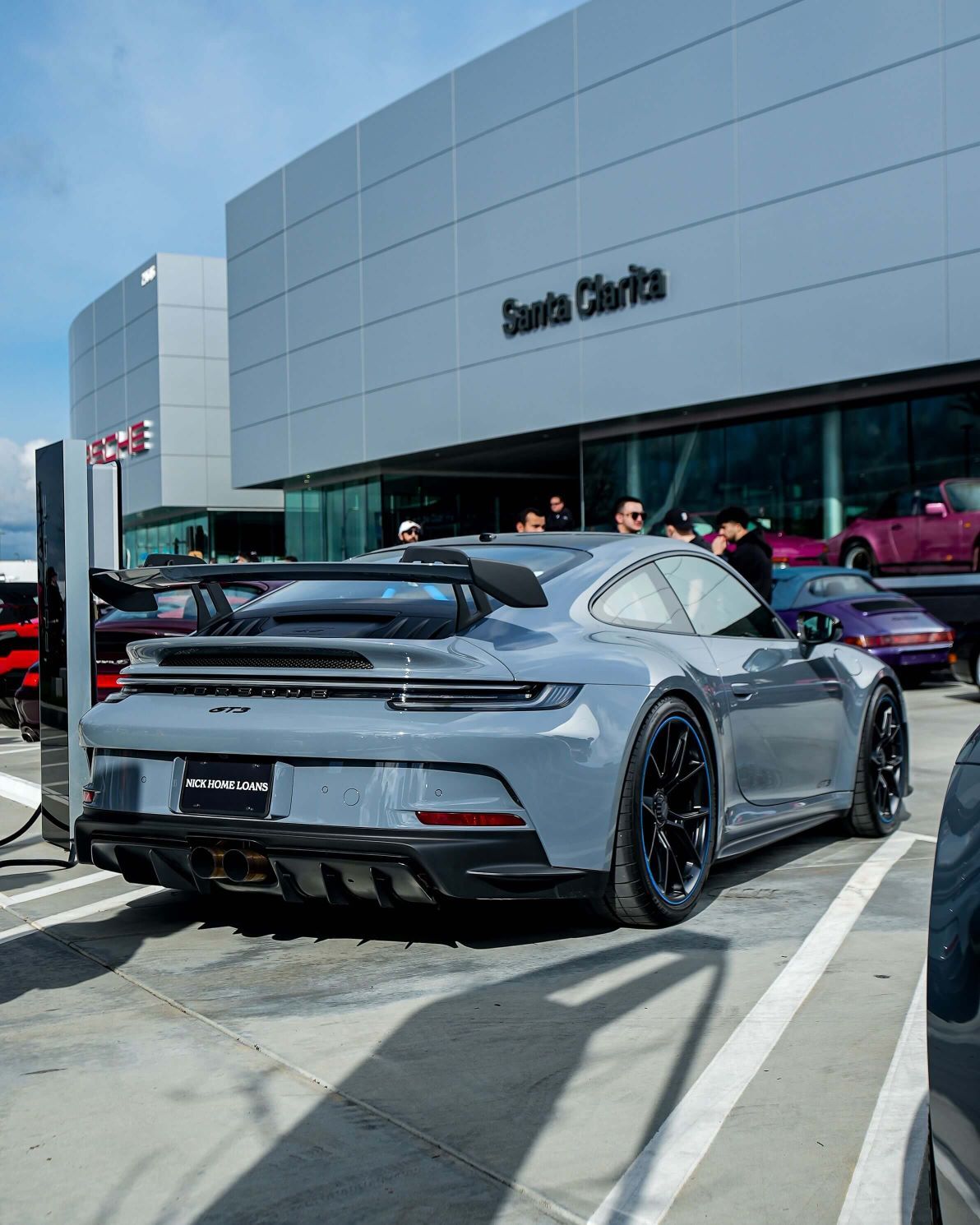 Rear view of a grey Porsche GT3 parked in front of a modern dealership building labeled Santa Clarita.
