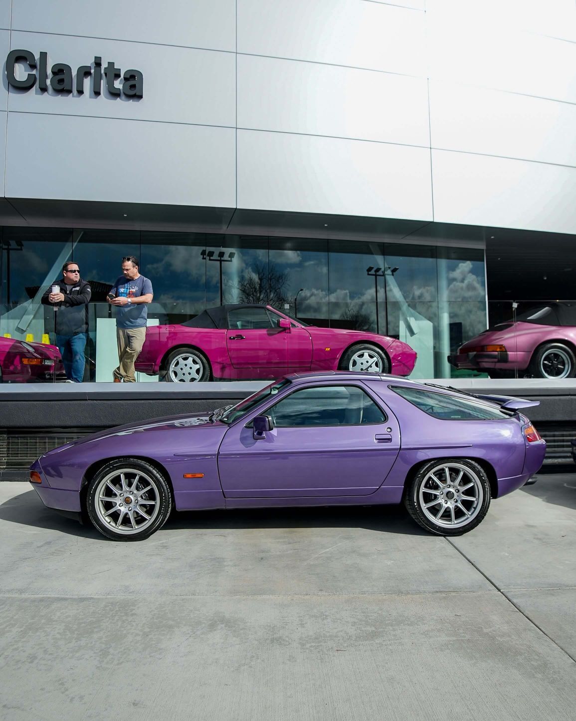 A vibrant purple sports car parked in front of a modern building with Clarita
on the facade.