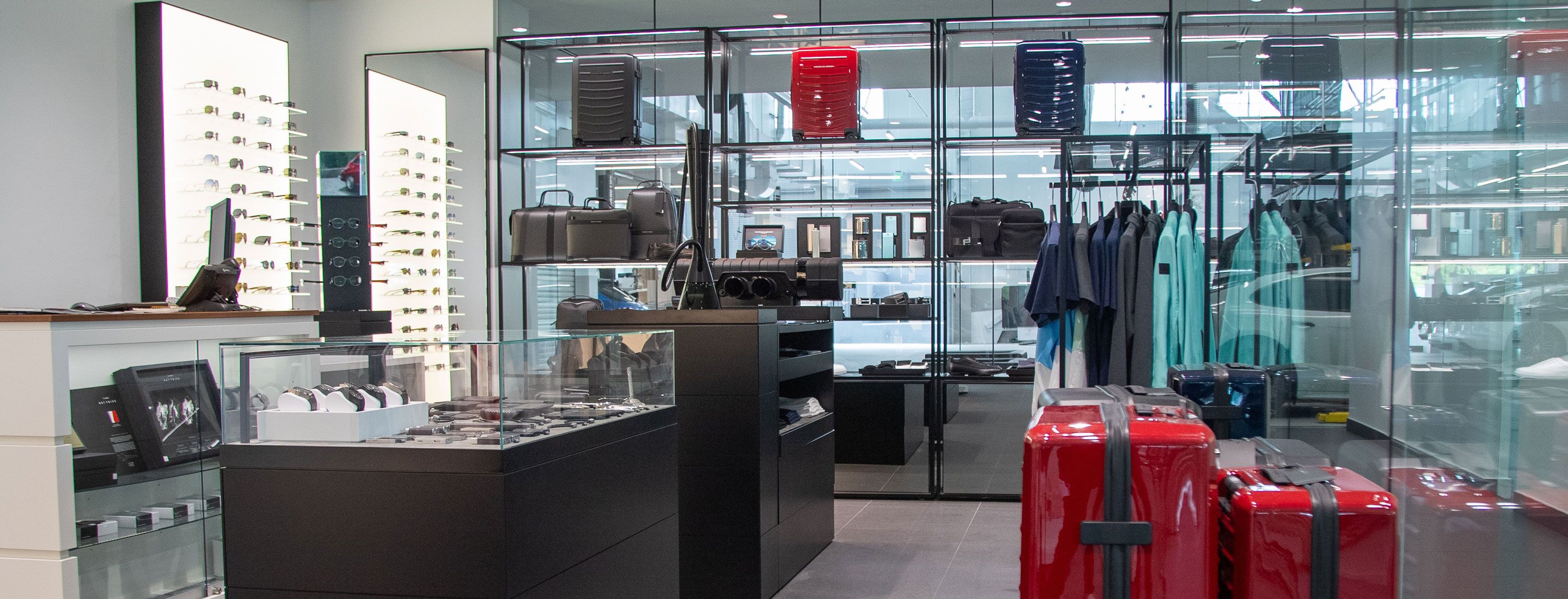 High-end retail store interior with modern luggage, sunglasses, and apparel displayed in glass and black metal fixtures.