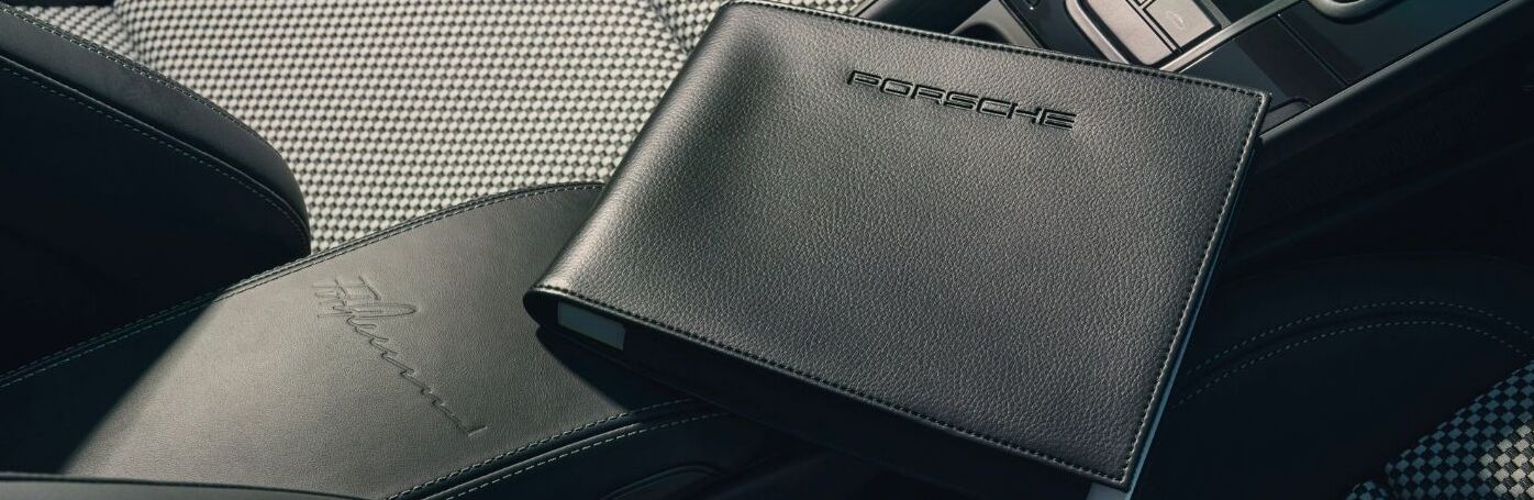 Porsche branded black leather folder placed on car seat interior