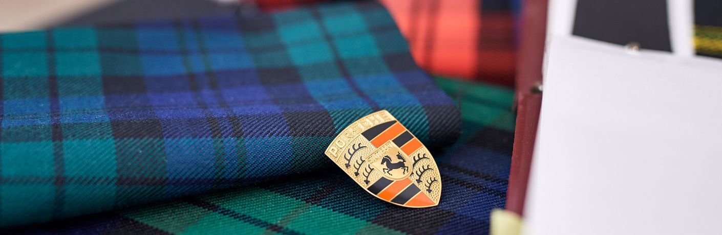 Porsche logo badge placed on blue and green checkered fabric