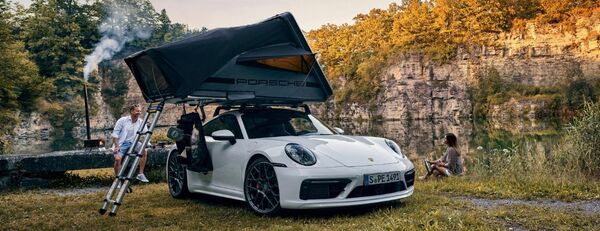 White Porsche sports car with rooftop tent parked outdoors