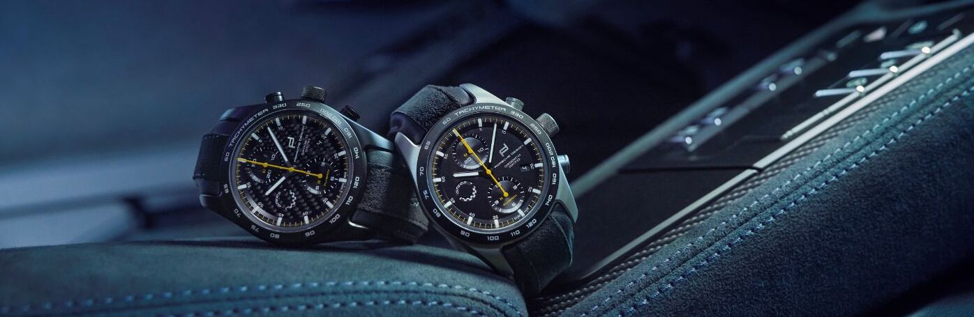 Two luxury Porsche Design watches resting on a car leather interior