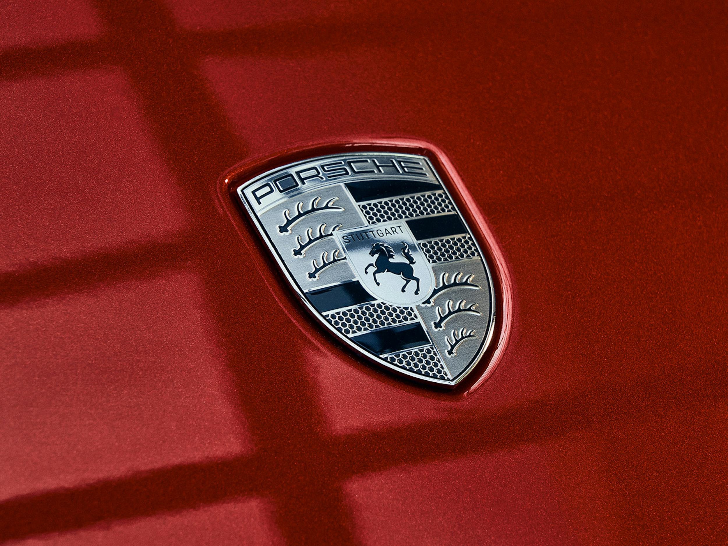 A close-up of the Porsche logo on a red car.