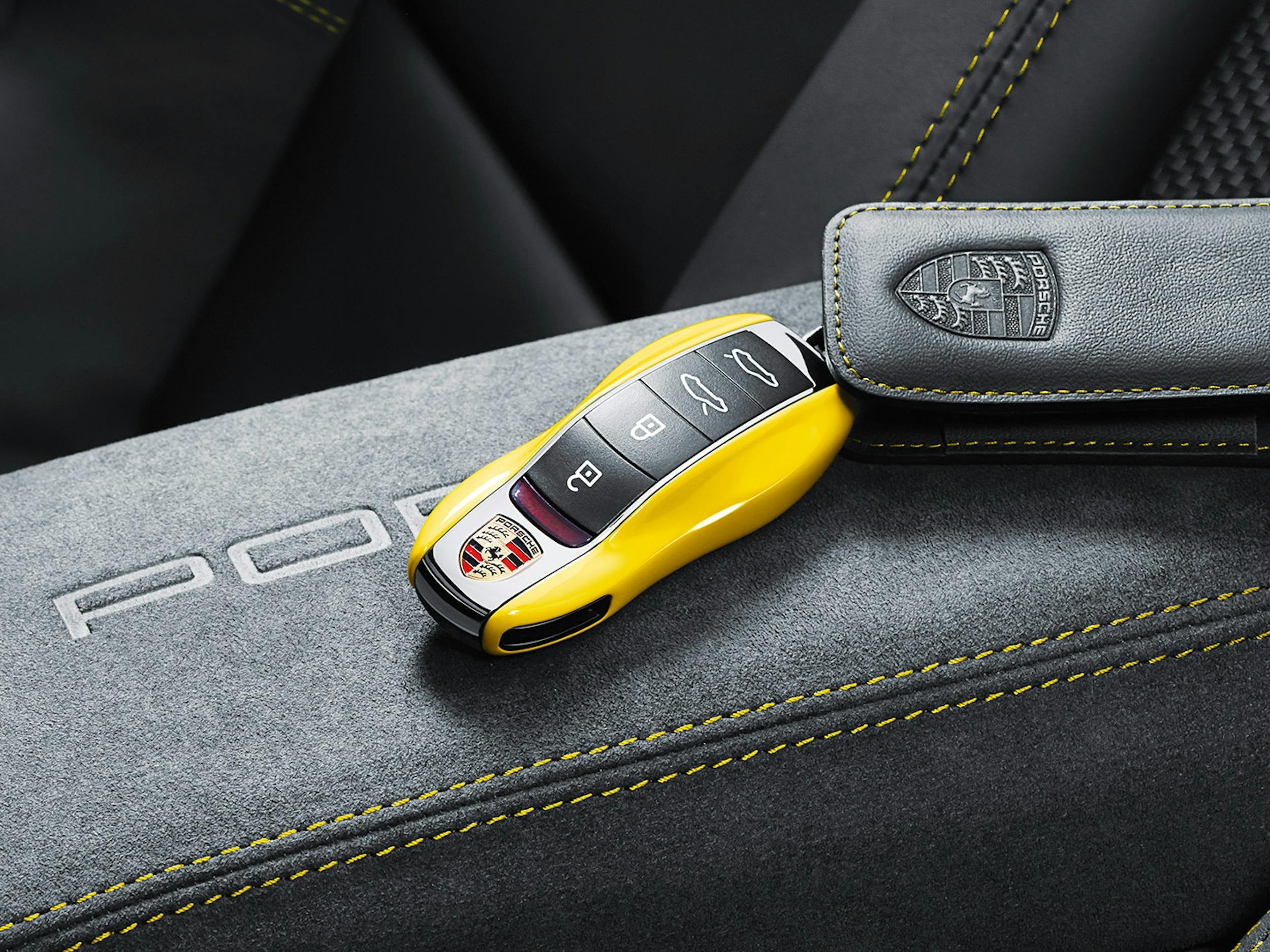 Yellow Porsche vehicle key fob resting on a Porsche interior surface.